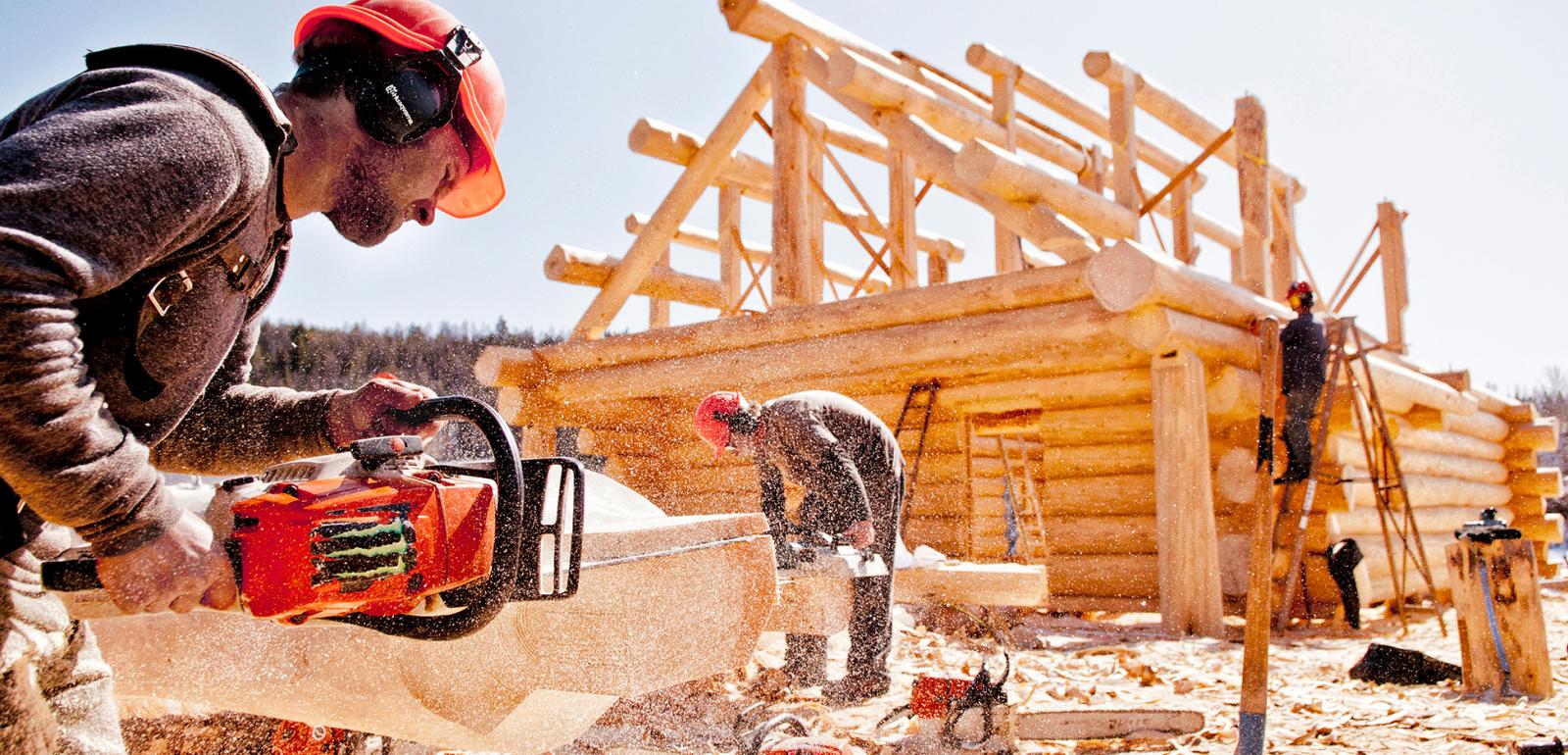 Worker using a chainsaw to build a timber frame home