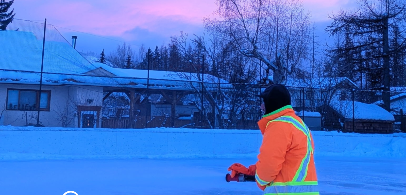 City staff member flooding outdoor ice rink using hose